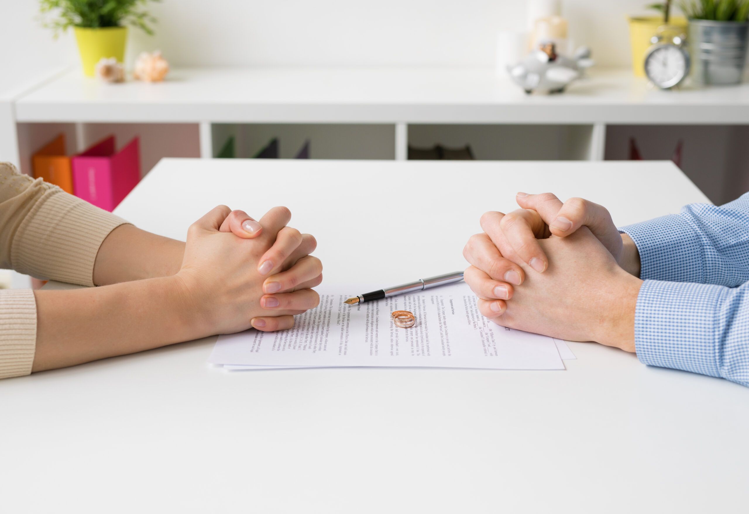 Hands of a couple facing each other at a table with wedding rings and a contract | Pennsylvania divorce arbitration lawyers | Vetrano | Vetrano & Feinman