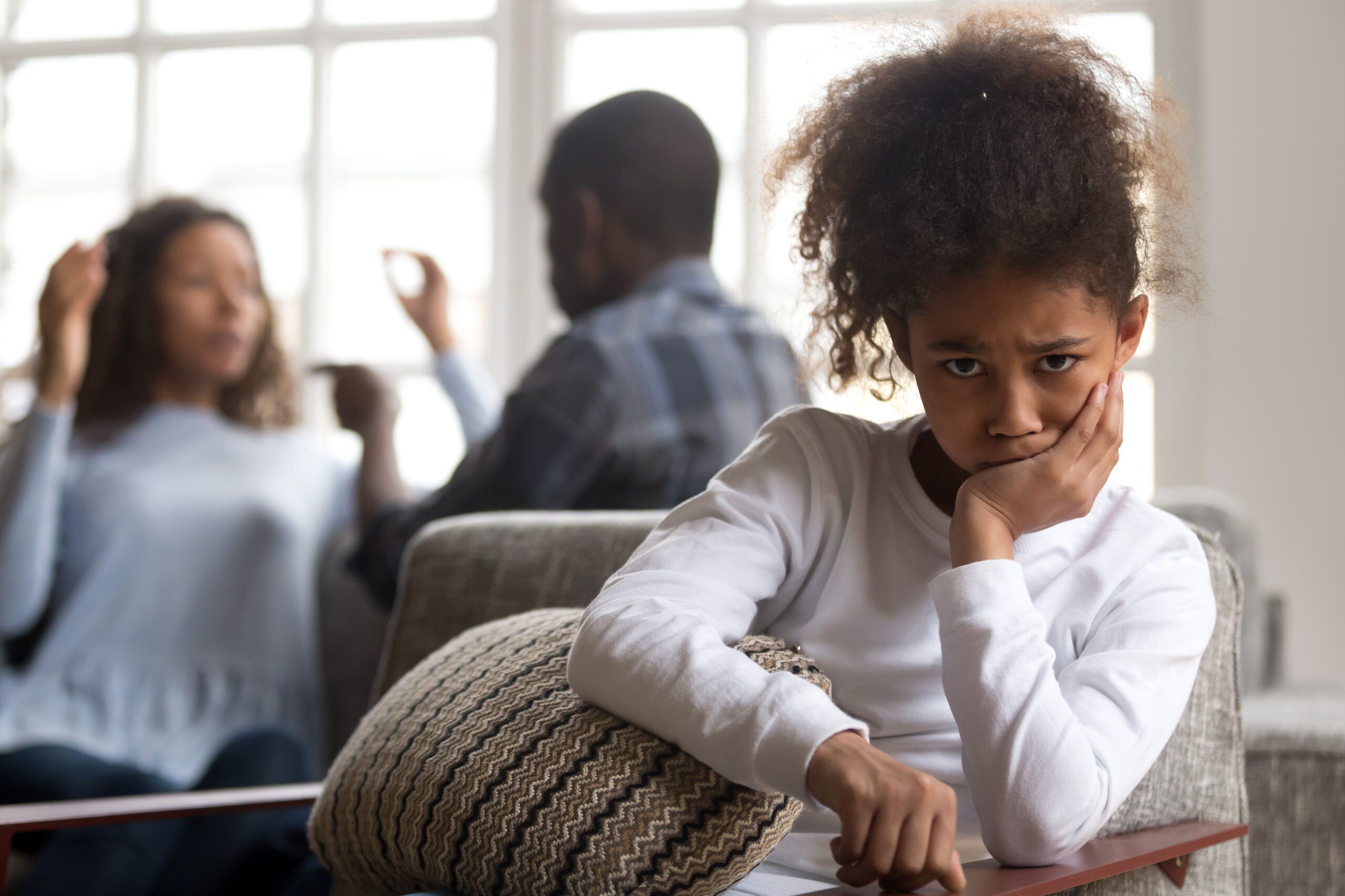 Unhappy child with arguing parents in the background | Philadelphia Child Support Lawyer